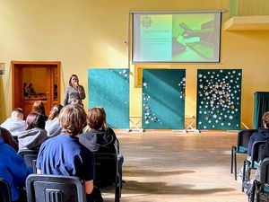 Na zdjęciu znajduje się policjantka "po cywilnemu", która przeprowadza prelekcję.
Na sali znajduje się młodzież. funkcjonariuszka wyświetla pokaz slajdów
