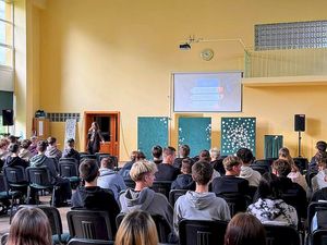 Na zdjęciu znajduje się policjantka "po cywilnemu", która przeprowadza prelekcję.
Na sali znajduje się młodzież. funkcjonariuszka wyświetla pokaz slajdów