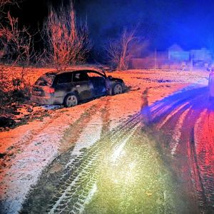 Samochód, koloru ciemnego, który znajduje się w przydrożnym rowie.