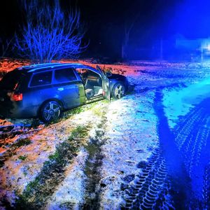Samochód, koloru ciemnego, który znajduje się w przydrożnym rowie.