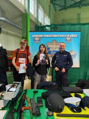 Zdjęcie uczestników targów wraz z funkcjonariuszem przy stoisku policyjnym